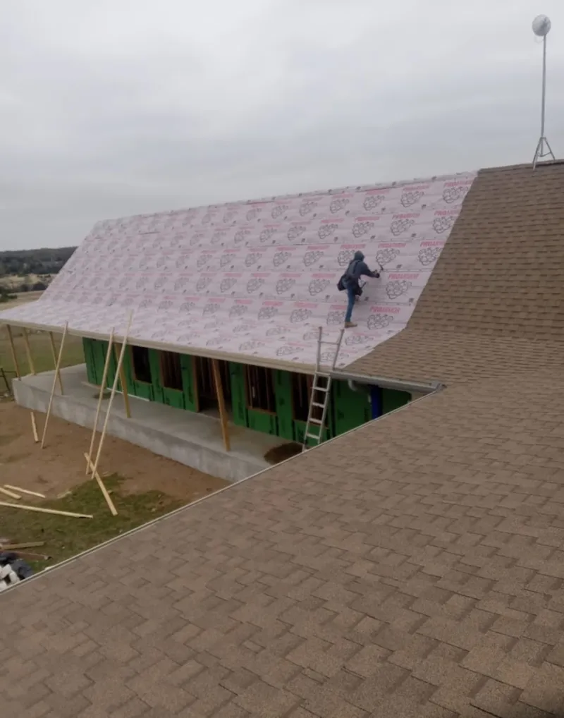 Worker preparing underlayment for a metal roof installation in Waynesville